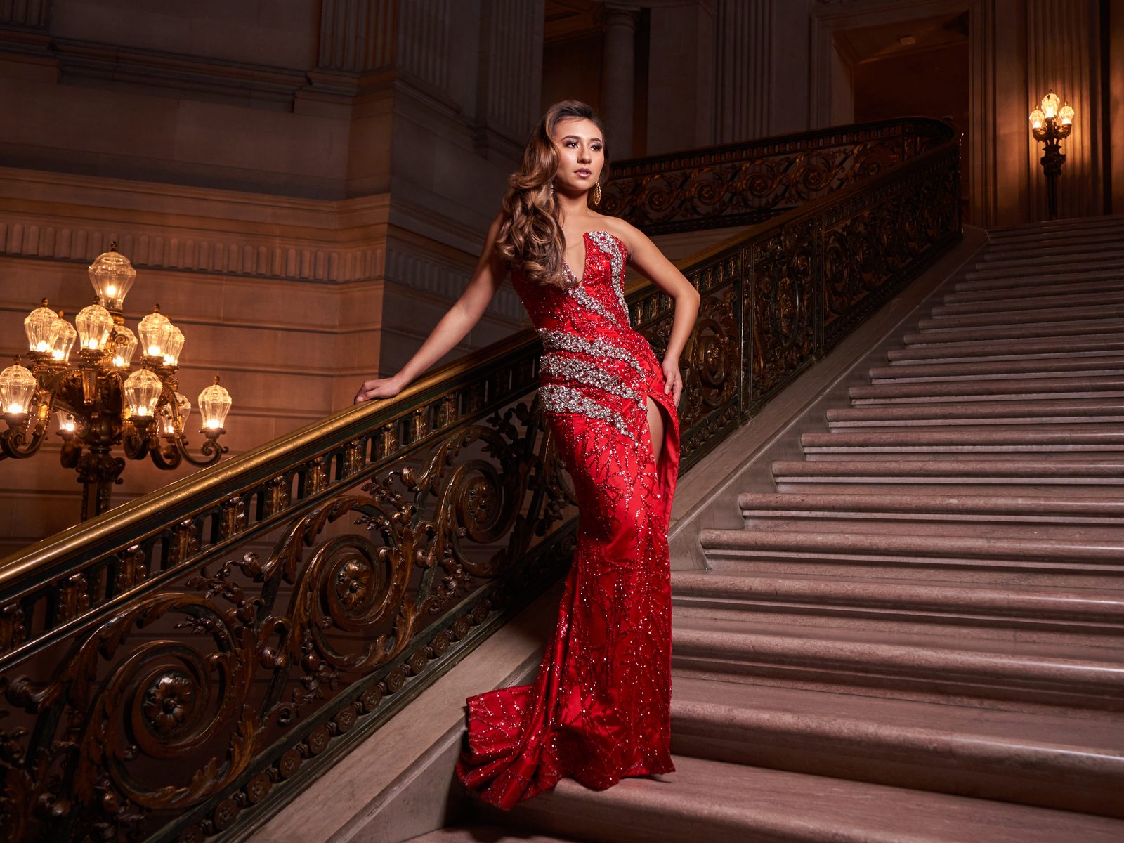 Red sequin gown on the grand staircase, chandelier beyond